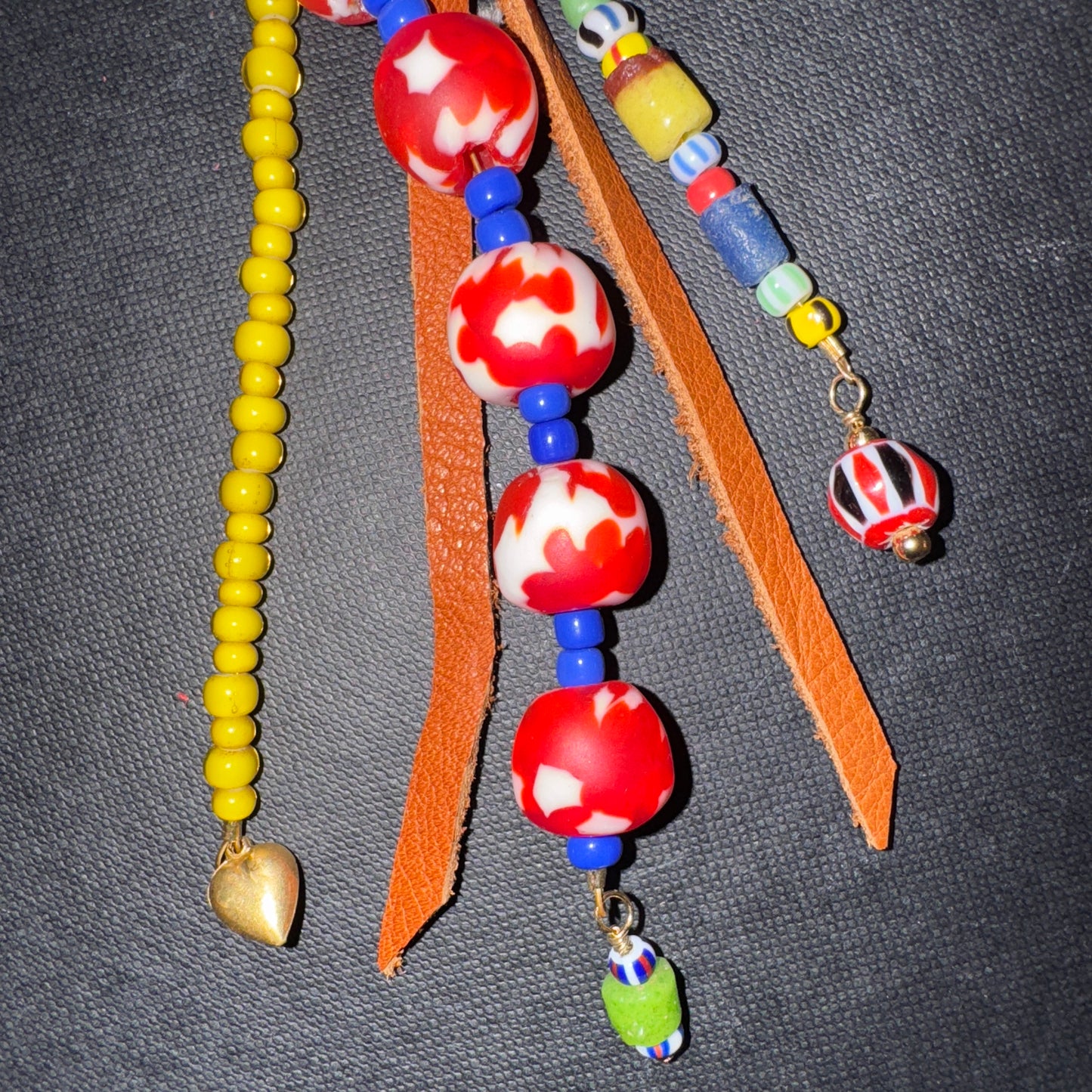 Colorful beaded necklace with red and white beads on a gray background