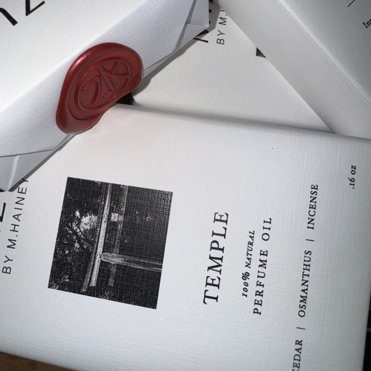 Perfume oil packaging with 'Temple' branding and a red wax seal.