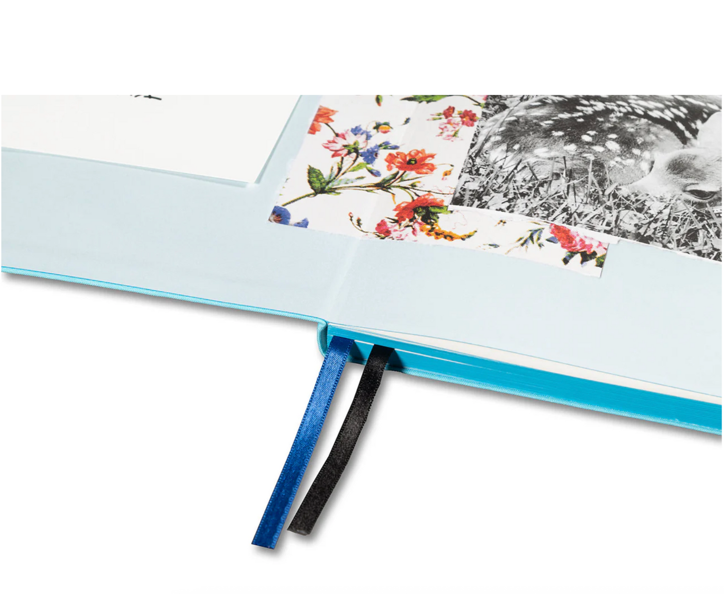 Open notebook with floral design on pages and a blue ribbon bookmark.