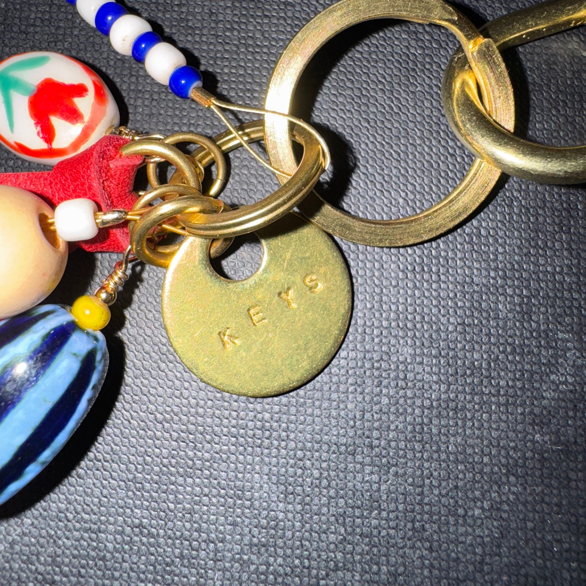 Keychain with colorful beads and a 'KEYS' tag on a dark textured surface